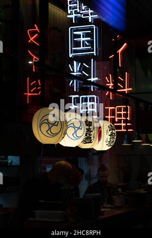 Chinese restaurant interior with neon light china characters and paper lanterns decoration on walls Stock Photo