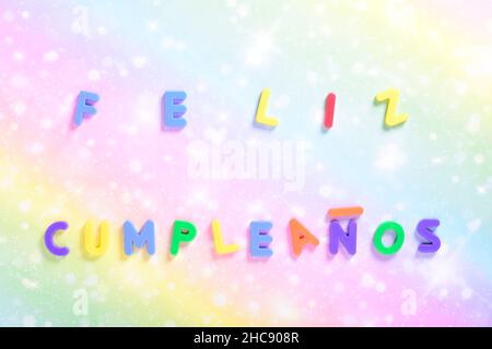 Photograph of some magnet letters with the Spanish text of Happy Birthday on a colored cardboard background.The photograph is shot in horizontal forma Stock Photo