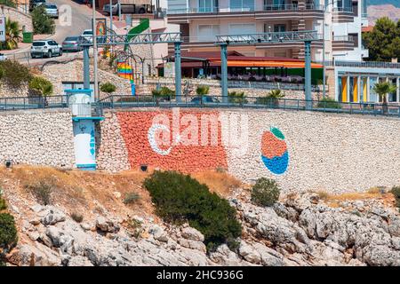 26 August 2021, Finike, Turkey: A resort town with Turkish flag painted on a stone wall Stock Photo