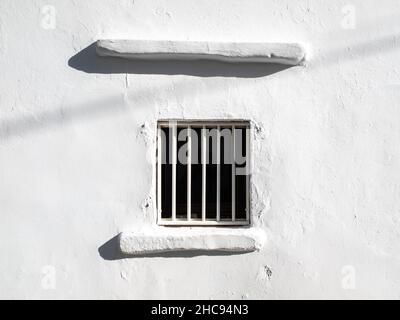Typical window with bars closed on a white wall house. Taken on a very sunny summer day in the Aegean Island of Santorini, Greece Stock Photo