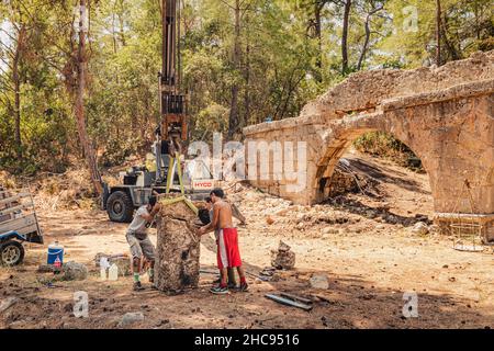 24 August 2021, Antalya, Turkey: Working archaeologists are working on historical excavations using a heavy crane machine in the ancient city of Phase Stock Photo