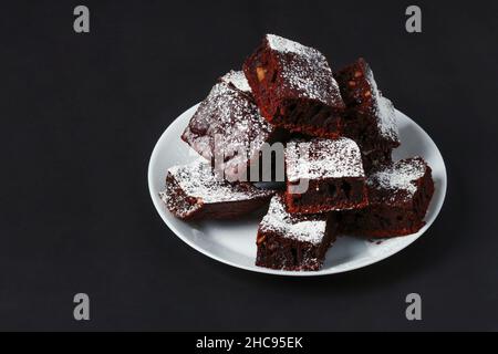 Pieces of coffee cake sprinkled with powdered sugar on a white porcelain plate Stock Photo