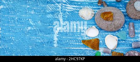 Sea pebbles and seashells on the table. A pyramid of sea stones on a blue background. Stock Photo