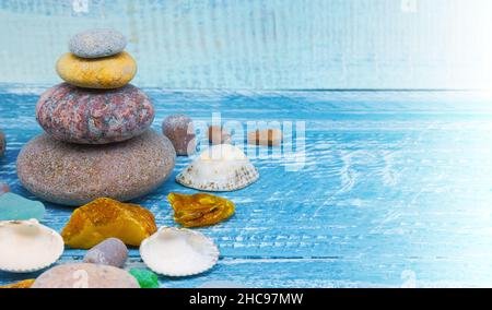 Sea pebbles and seashells on the table. A pyramid of sea stones on a blue background. Stock Photo