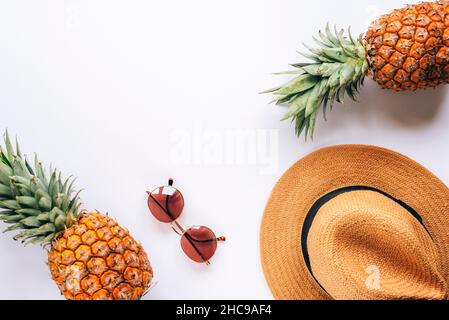 Women's summer accessories, hat, sunglasses and pineapples. Beauty, fashion, summer vacation concept. Top view, flat lay, copy space. Stock Photo