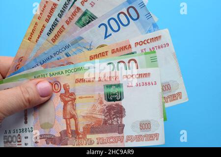 Russian ruble banknotes in a female hand on a blue background. Stock Photo