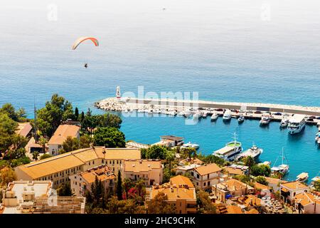 Charming view of the seaside resort town of Kas in Turkey. Romantic lighthouse at the entrance to the port and a paraglider flies over the marina Stock Photo