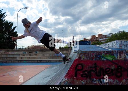 young blond boy performing skateboarding tricks jumping in the skatepark Stock Photo