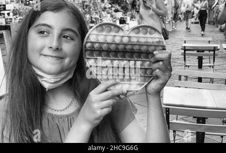 Grayscale shot of an Italian young girl with a heart-shaped pop it Stock Photo