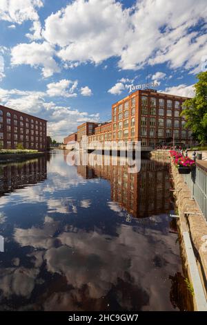 Old red brick industrial buildings along the Tammerkoski rapids in downtown Tampere, Finland, on a sunny day. Stock Photo