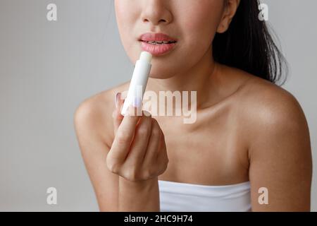 Asian young woman applying hygienic lipstick in studio Stock Photo