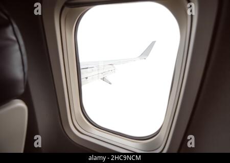 Isolated and cutout on white view from the passenger seat to the porthole and the wing of the aircraft. Stock Photo