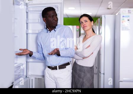 Interracial couple choosing fridge Stock Photo