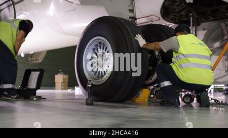 Airport worker checking chassis. Engine and chassis of the passenger airplane under heavy maintenance. Engineer checks the aircraft chassis and engine Stock Photo