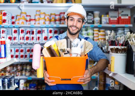 Workman holding basket with picked tools in paint store Stock Photo