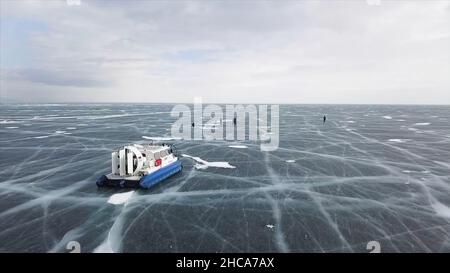 Aerial view of the machine moving on the frozen amazing lake. Typical hovercraft vehicle on clear craked ice surface, Lake Baikal, Siberia, Russia. Stock Photo