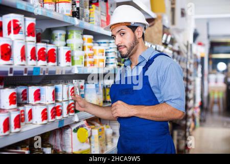Focused workman choosing materials for renovation works in paint store Stock Photo