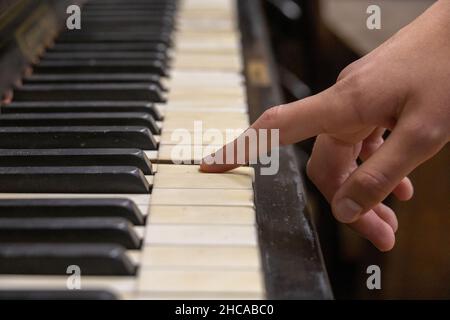Close-up shot of a finger pressing an old vintage piano key Stock Photo