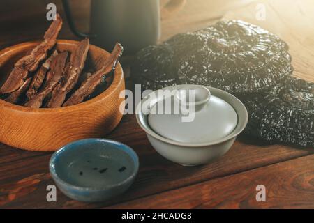 Brewed Dried Chinese Lingzhi in bowl and sliced pieces of Ganoderma Lucidum or Reishi mushroom in plate on wooden table. Asian herbs for health. Stock Photo