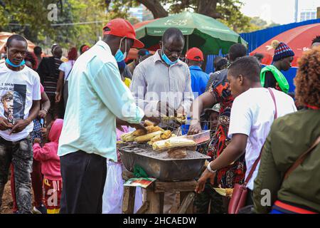 Nairobi, Kenya. 25th Dec, 2021. Kenyans buy roast maize from a vendor on Christmas Day. For many years, Kenyans living in Nairobi and its environs have spent Christmas Day at the Uhuru and Central parks. However, that is not the case this year, as the two parks remain closed for renovations. This did not stop them from enjoying the day in small spaces that were available. (Photo by Boniface Muthoni/SOPA Images/Sipa USA) Credit: Sipa USA/Alamy Live News Stock Photo