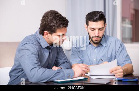 Two serious males with documents at table Stock Photo
