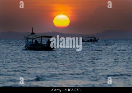 Sunset seen from Ribeira beach in Salvador, Bahia, Brazil. A boat sails at sea. Stock Photo