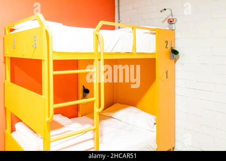 Yellow Lockers and Bunk beds with freshly made beds in a modern hostel room Stock Photo