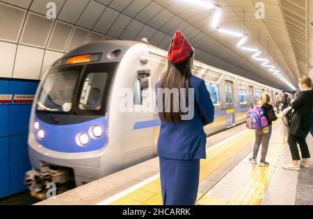 Train arrives in Baykonur metro subway station in Almaty, Kazakhstan, Central, Asia. Female metropolitain employee worker controlling the traffic. Stock Photo