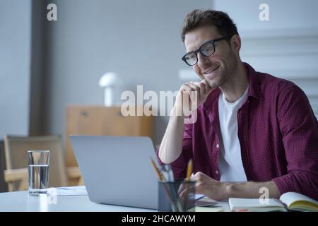 Young handsome smiling german man office worker in glasses enjoying video call on laptop computer Stock Photo