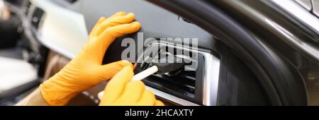 Master repairman in rubber gloves cleaning car air conditioner with brush in workshop closeup Stock Photo