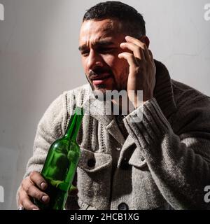Alcoholic man with bottles wine cry. Depressed crying man. Drunk men drinking alcohol feeling lonely and desperate in emotional stress. Stock Photo