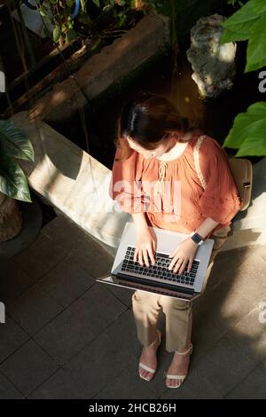 Young female software developer working on laptop, view from above Stock Photo