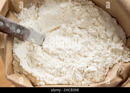 Overview of pile of fresh wheat flour in eco-friendly paper sack and spoon for taking it out Stock Photo