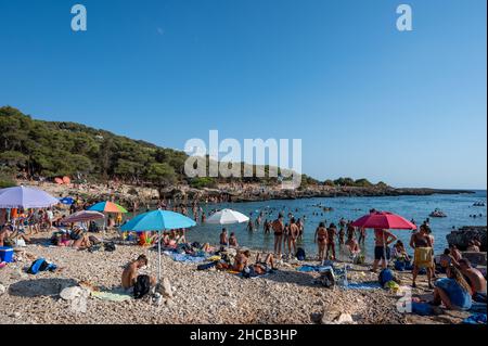 Porto Selvaggio, Puglia, Italy. August 2021. Stunning view of the bay packed with tourists intent on sunbathing or swimming. Concept of beach holidays Stock Photo