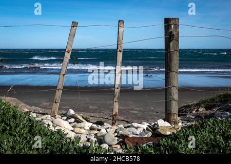 Post and wire fence beside beach at Glenburn, Wairarapa, North Island, New Zealand Stock Photo