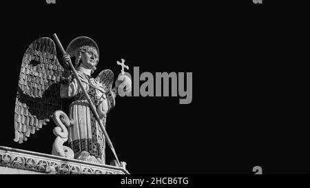 Saint Michael the Archangel defeats the Dragon, a medieval 13th century statue a the top of St Michael Church in Lucca (Black and White with copy spac Stock Photo