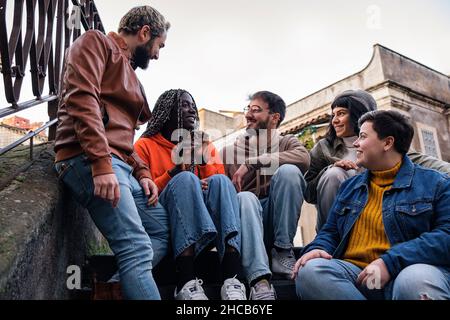 Multiracial best friends talking together sitting outdoors Stock Photo