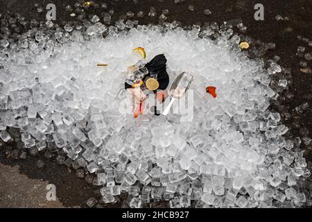 Leftover ice cubes with metal ice scoop in restaurant backyard Stock Photo