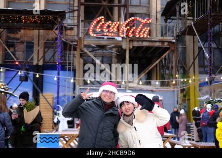 Minsk, Belarus, December 25, 2021: New Year's fair. Portrait of a chinese man and woman wearing santa claus hats Stock Photo