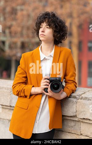 Young brunette woman with curly hair posing with her camera Stock Photo