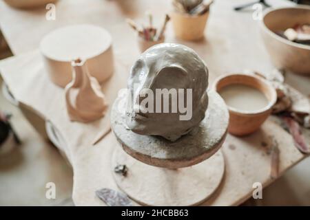 Close-up of clay sculpture of human face on pottery wheel in workshop Stock Photo