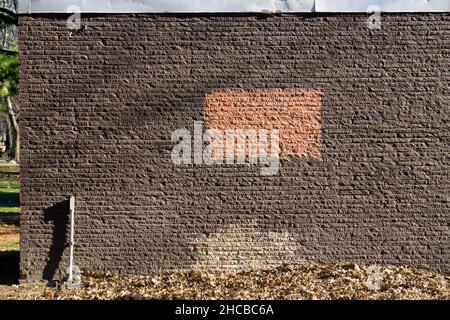 A wall on a small building with a rectangular box, a pipe & some lights and shadows. In Flushing Meadows Corona Park in Queens, New York. Stock Photo