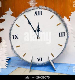 Homemade Christmas clock made of paper or cardboard. It's five minutes to twelve on the clock Stock Photo