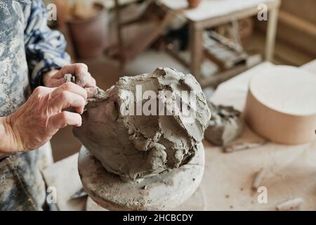 Close-up of potter using pottery wheel to make ceramic sculpture, he making features of the human face Stock Photo