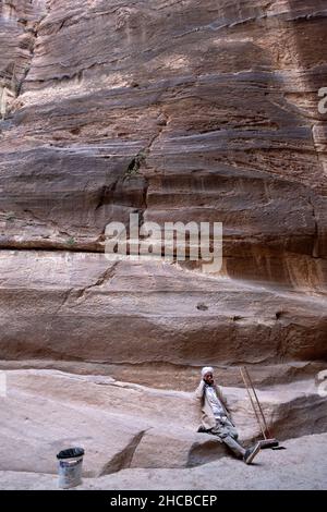 A working cleaner takes a cigarette and cell phone break in the ancient Jordanian city of Petra. Stock Photo