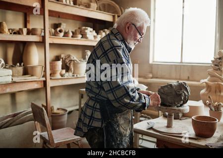 Senior man shaping clay sculpture on pottery wheel in the pottery studio Stock Photo