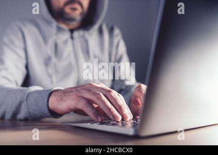 Grey hat hacker concept, man working on laptop to discover weaknesses in computer network, selective focus Stock Photo
