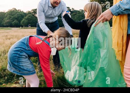 Daughters helping parents collecting garbage in park Stock Photo