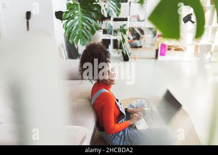 Curly haired woman using laptop at home Stock Photo