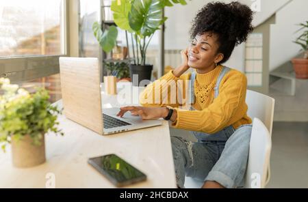 Smiling woman greeting on video call through laptop at table Stock Photo